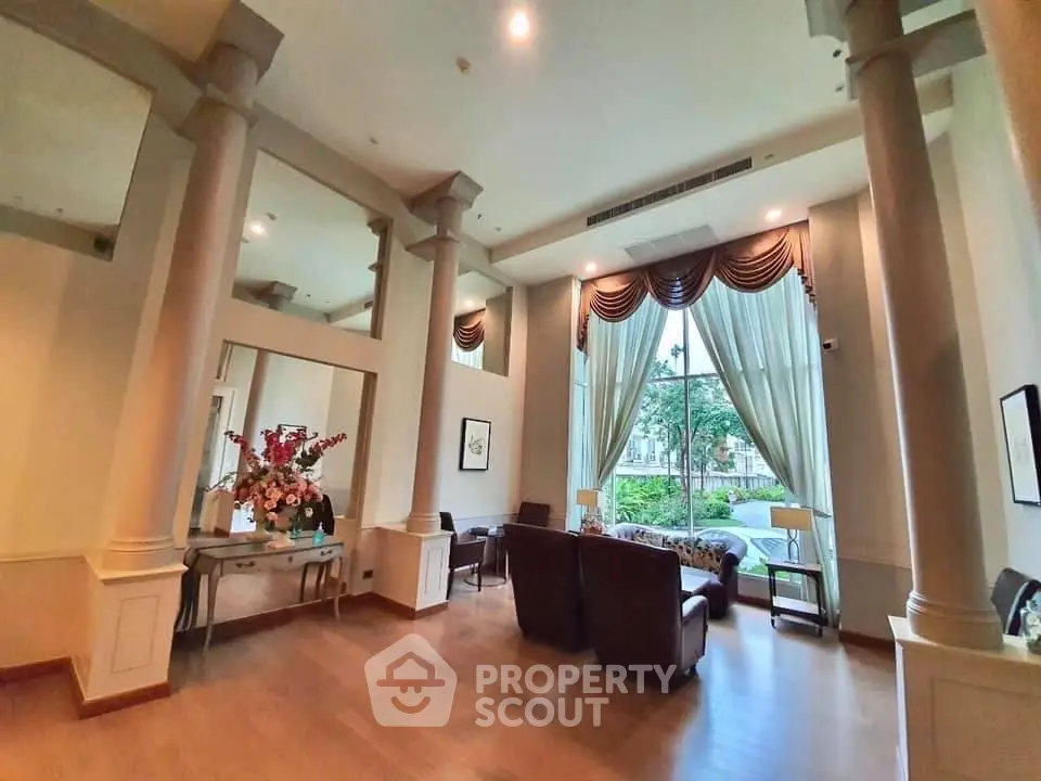 Elegant living room with high ceilings and large windows offering a garden view