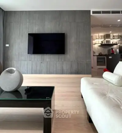 Modern living room with sleek design and open kitchen layout, featuring a wall-mounted TV and stylish furniture.