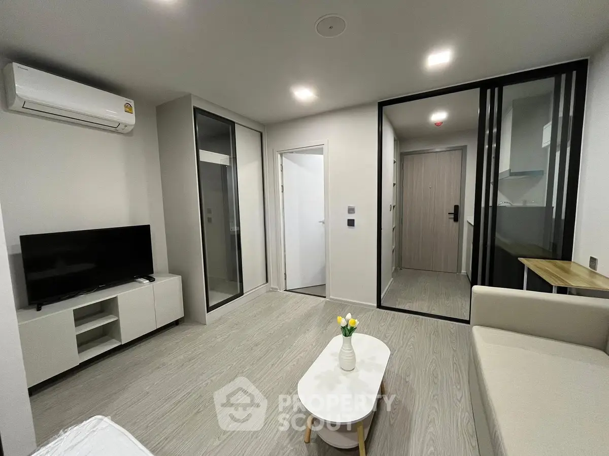 Modern living room with sleek design, featuring a TV, air conditioning, and stylish furniture.