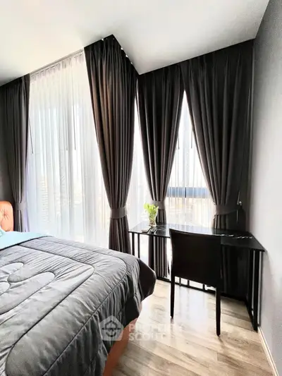 Modern bedroom with stylish curtains and a cozy workspace by the window.