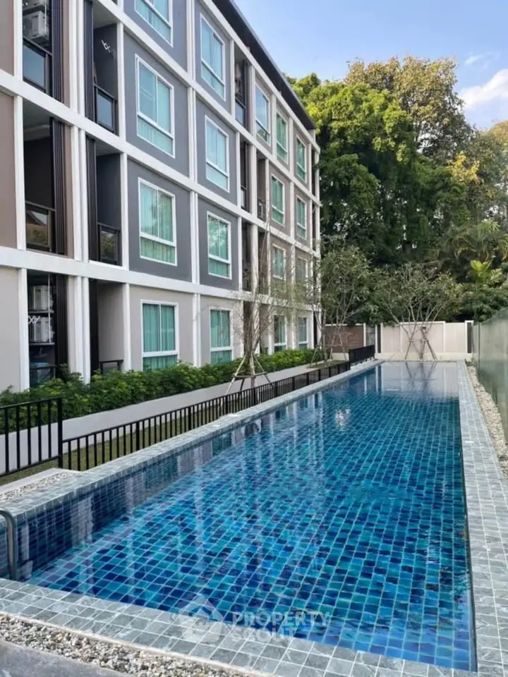 Modern apartment building with a sleek outdoor pool and lush greenery.
