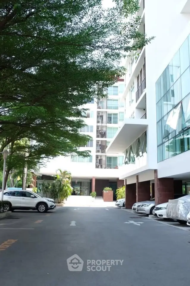 Modern apartment building exterior with parking area and lush greenery