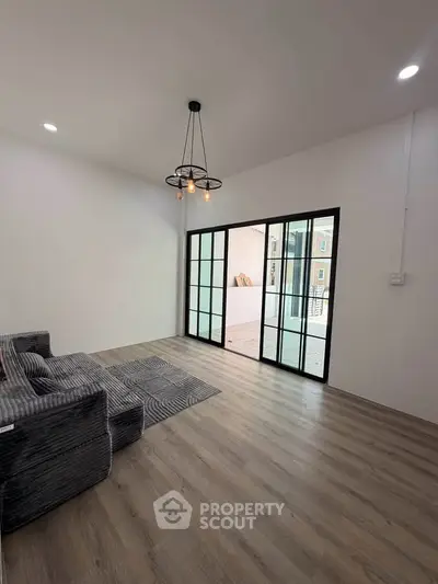 Modern living room with stylish lighting and sliding glass doors leading to balcony.