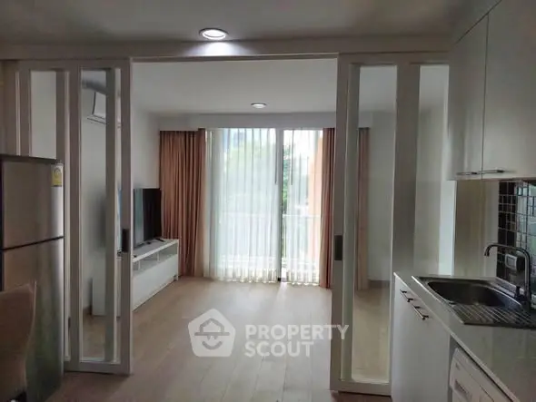 Modern open-plan living room with kitchen, featuring sleek design and natural light.
