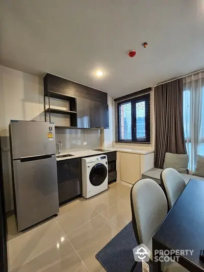 Modern kitchen with sleek appliances and cozy dining area in stylish apartment.