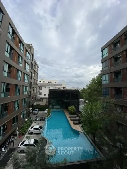 Modern apartment complex with a central swimming pool and lush greenery.