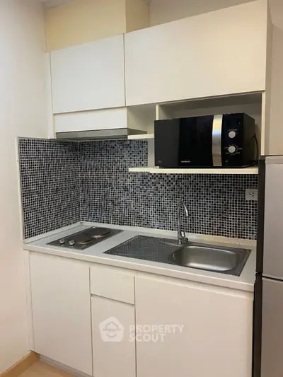 Compact modern kitchen with mosaic backsplash and built-in appliances