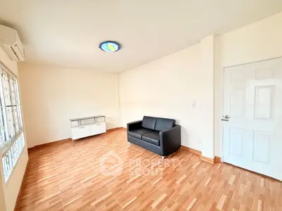 Spacious living room with modern sofa and natural light, perfect for relaxation.