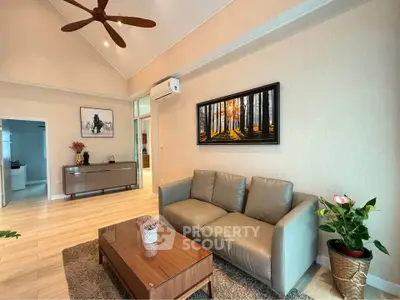 Spacious living room with modern decor and high ceiling, featuring a cozy sofa and elegant artwork.