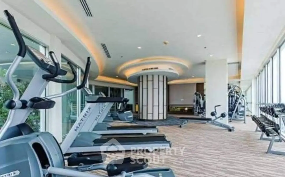 Spacious modern gym with state-of-the-art equipment and panoramic windows in luxury building.