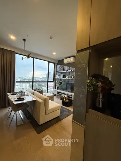 Modern living room with city view, elegant decor, and cozy dining area