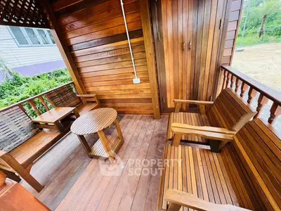 Charming wooden balcony with cozy seating in serene outdoor setting.