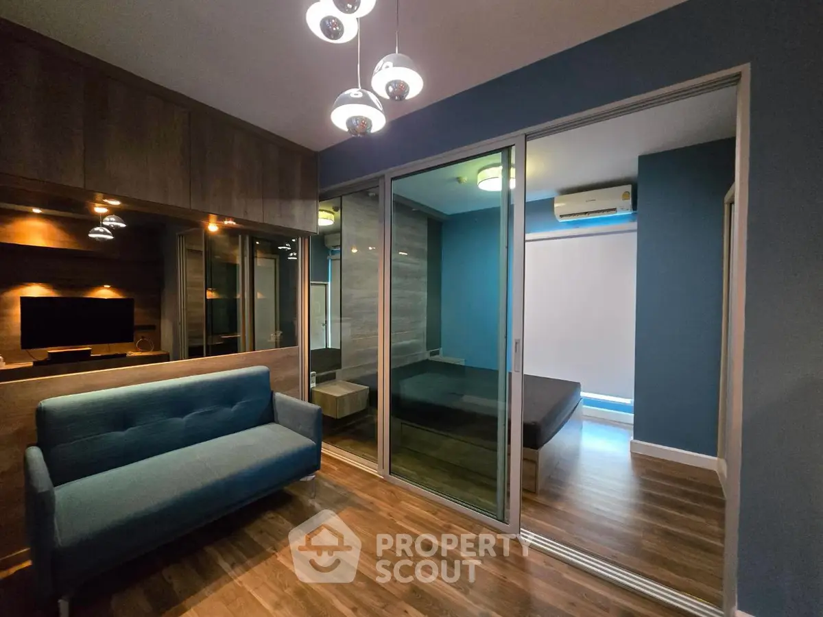 Modern living room with sleek design and glass partition leading to bedroom