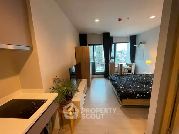 Modern studio apartment with open layout and city view, featuring cozy bedroom and compact kitchen.