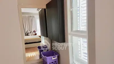 Modern bedroom with large mirror and natural light, featuring stylish decor and ample storage space.