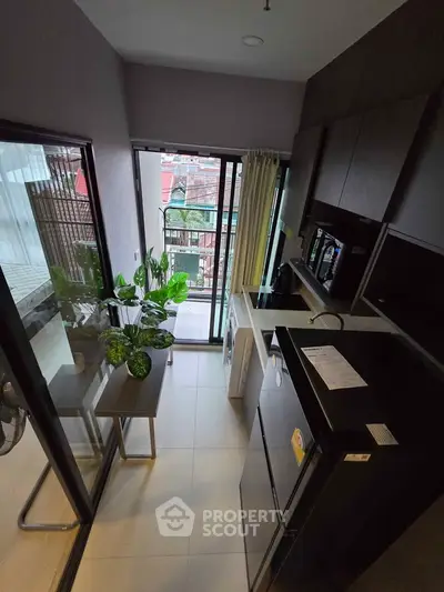 Modern kitchen with balcony view, featuring sleek appliances and stylish decor in a compact layout.