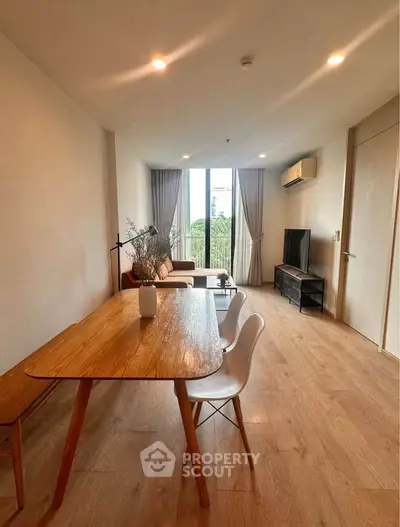 Spacious modern living room with wooden flooring and large window view.
