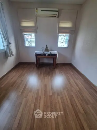 Spacious room with wooden flooring and air conditioning, ideal for versatile use.