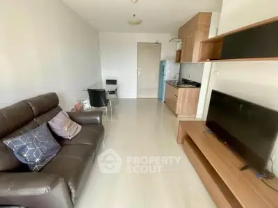 Modern living room with sleek furniture and compact kitchen area.