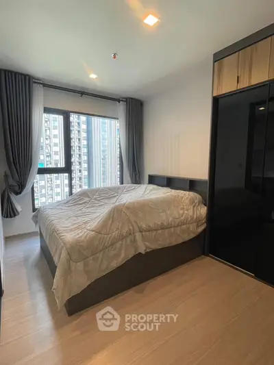 Modern bedroom with large window and city view in a high-rise apartment