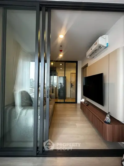 Modern living room with sliding glass doors and wall-mounted TV in a stylish apartment.