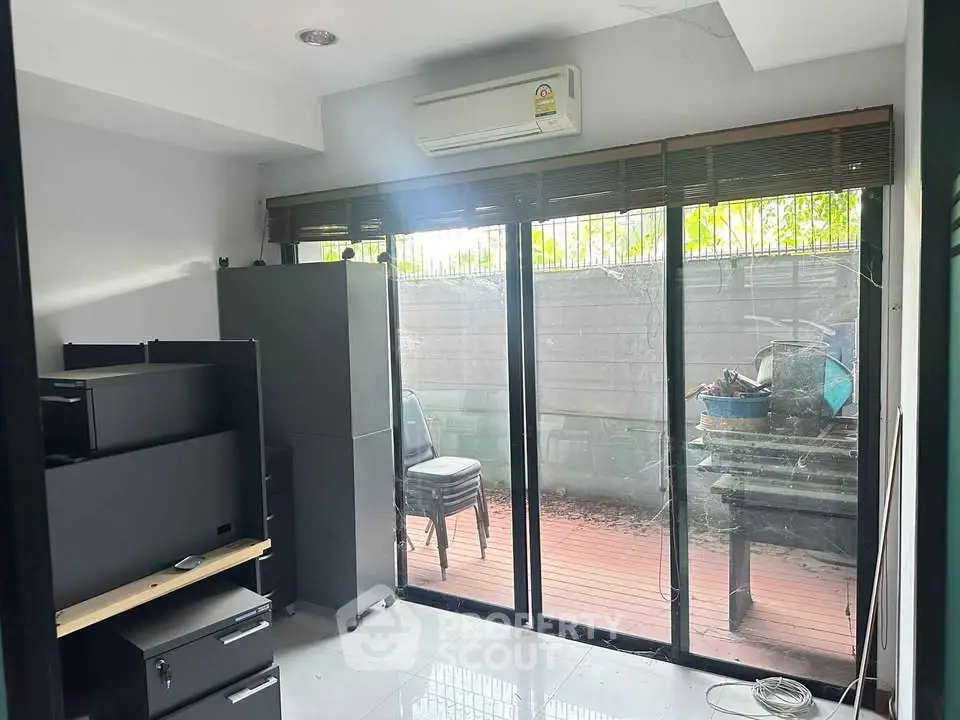 Cozy home office with sliding glass doors leading to a private patio, featuring modern furniture and ample natural light.