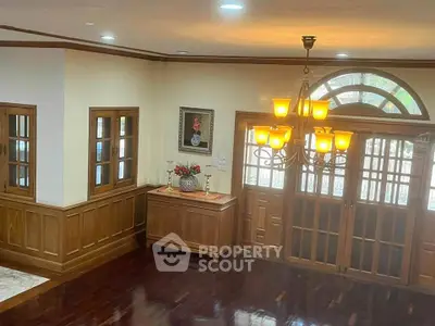 Elegant living room with wooden flooring and chandelier, showcasing classic design and warm ambiance.
