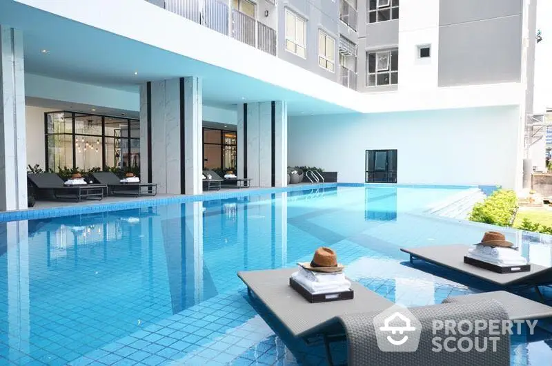 Luxurious modern apartment with stunning poolside view and stylish lounge chairs.