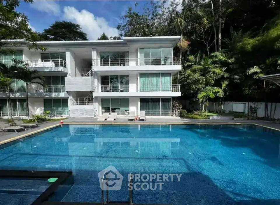 Luxurious apartment complex with a stunning pool and lush greenery.