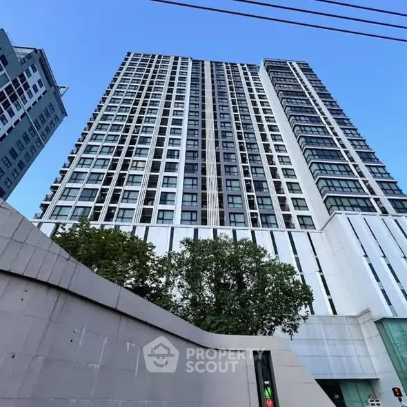 Modern high-rise building with sleek design and large windows under a clear blue sky.