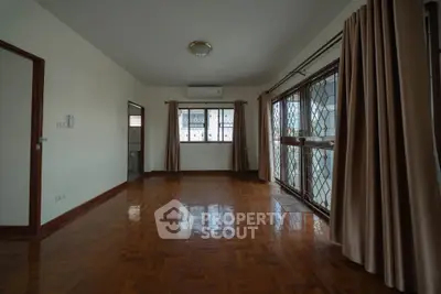 Spacious living room with polished wooden floors and large windows for natural light.