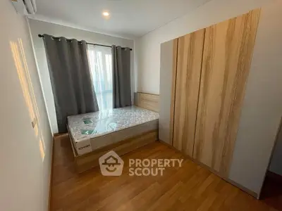 Modern bedroom with wooden flooring and large window for natural light