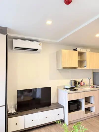 Modern kitchen with sleek cabinetry, TV, and air conditioning in a stylish apartment.