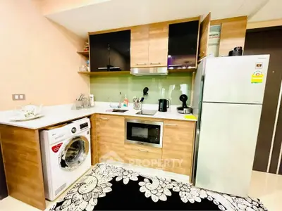 Modern kitchen with washing machine, microwave, and fridge in compact layout.