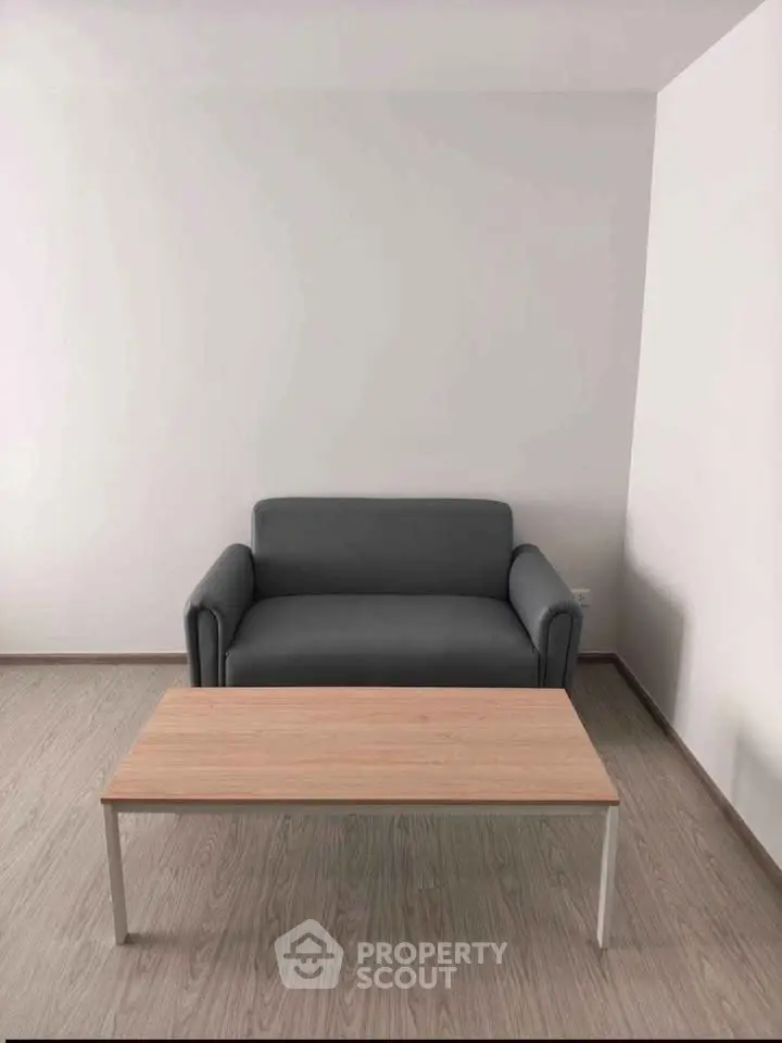 Minimalist living room with gray sofa and wooden coffee table on light wood flooring.