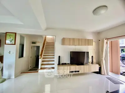 Spacious modern living room with sleek TV setup and staircase leading to upper floor.