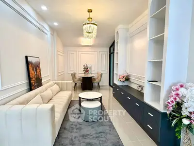 Elegant living room with plush sofa, modern chandelier, and stylish decor in a contemporary apartment.