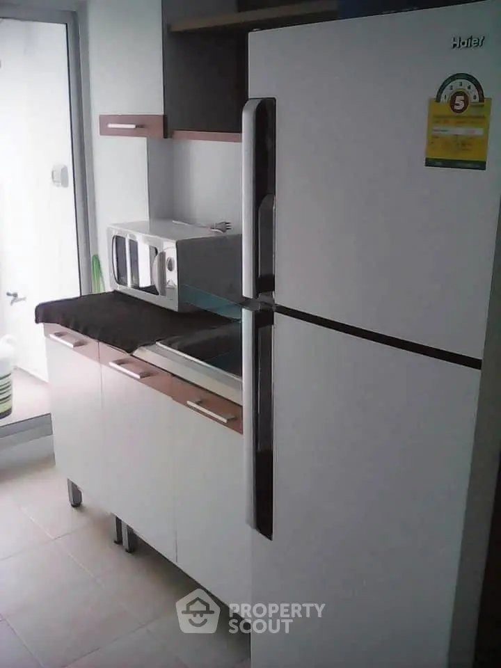 Modern kitchen with sleek refrigerator and microwave, perfect for contemporary living.