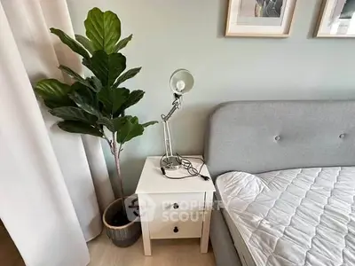 Cozy bedroom corner with stylish lamp and lush plant beside a modern bed.
