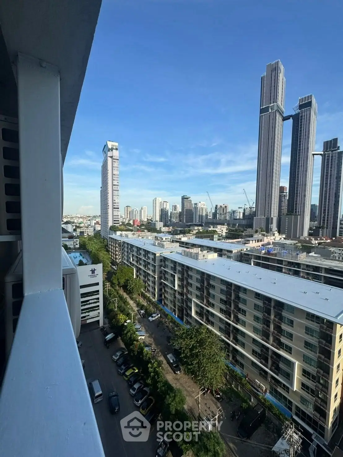 Stunning cityscape view from a high-rise balcony overlooking modern skyscrapers and urban landscape.