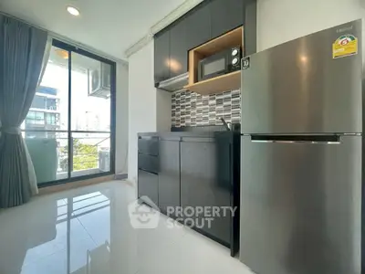 Modern kitchen with sleek black cabinets and stainless steel appliances in a bright apartment.