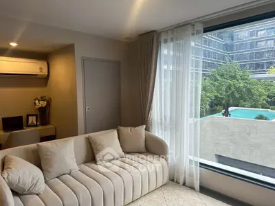 Modern living room with pool view, featuring elegant sofa and large window for natural light.