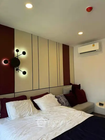 Modern bedroom with stylish wall decor and cozy bedding, featuring ambient lighting and air conditioning.