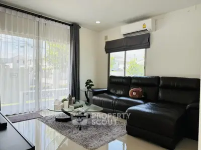 Modern living room with leather sofa and glass coffee table, bright and airy ambiance.