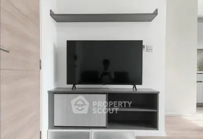 Modern living room with sleek TV stand and wall-mounted shelf, showcasing minimalist design.