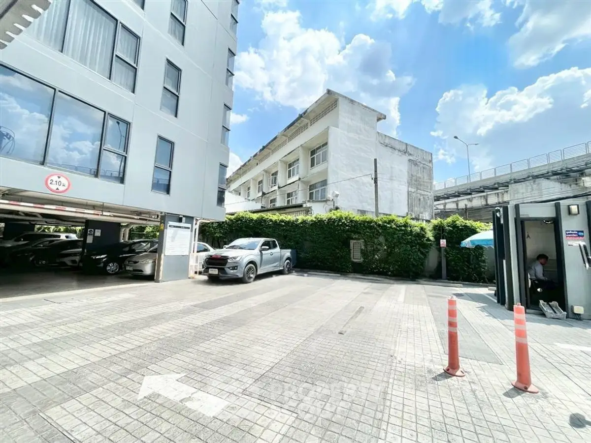 Modern building exterior with parking area under a bright blue sky, showcasing urban living convenience.