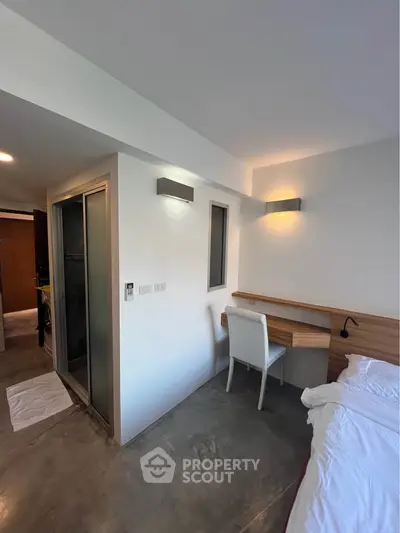 Modern bedroom with study area and minimalist design, featuring sleek lighting and a cozy atmosphere.