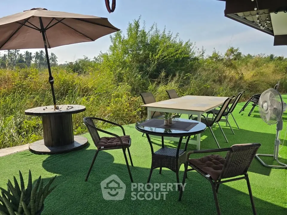 Charming outdoor seating area with lush greenery and modern furniture, perfect for relaxation and gatherings.