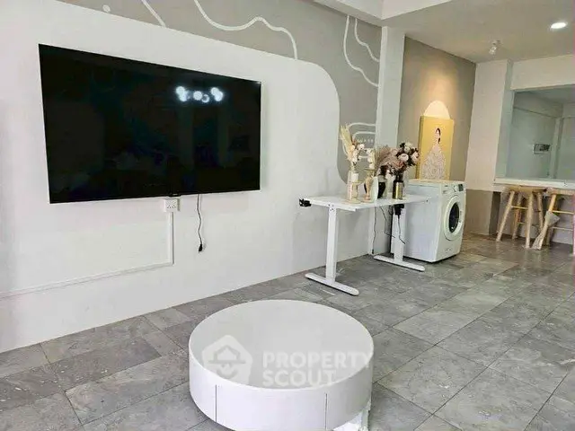 Modern living room with wall-mounted TV and washing machine in stylish apartment.