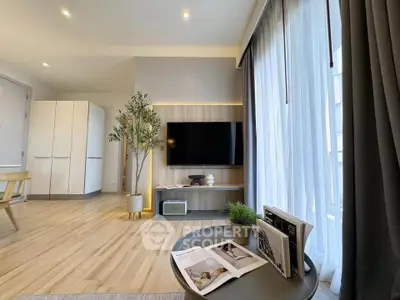 Modern living room with sleek design, large TV, and natural light through sheer curtains.